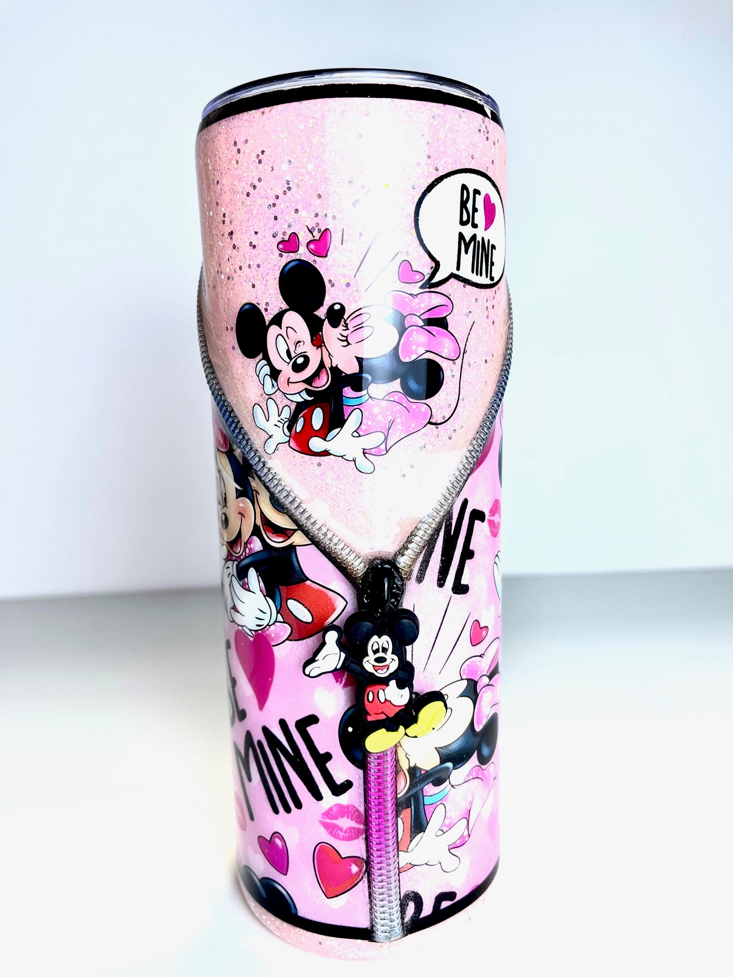 Pink tumbler with zipper style cartoon characters and 'Be Mine' text on a white background