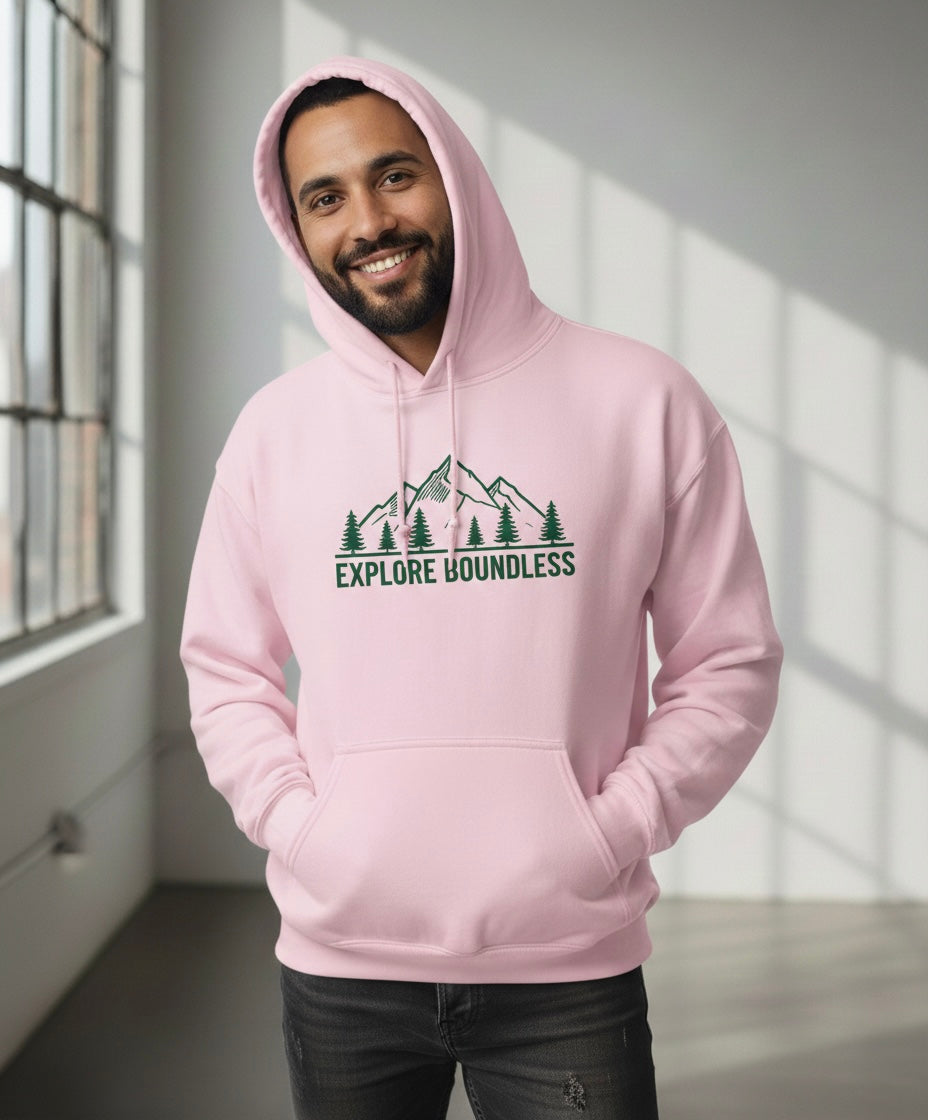 Man wearing a pink hoodie with 'Explore Boundless' design in a bright room.